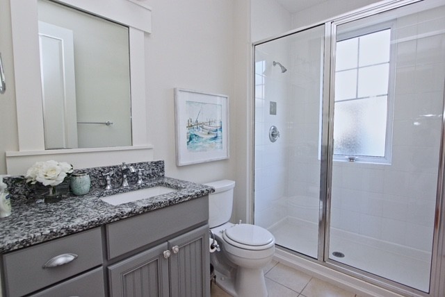 На фото: туалет в морском стиле с фасадами в стиле шейкер, серыми фасадами, белой плиткой, керамической плиткой, белыми стенами, полом из керамической плитки, врезной раковиной, столешницей из гранита и белым полом с