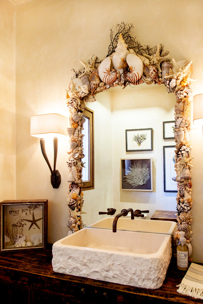 Mid-sized beach style powder room photo in San Francisco with wood countertops, beige walls, furniture-like cabinets, distressed cabinets, a trough sink and brown countertops