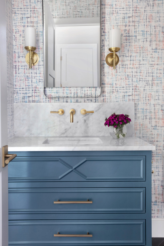 Cette image montre un WC et toilettes traditionnel avec un placard avec porte à panneau encastré, des portes de placard bleues, un carrelage multicolore, un lavabo encastré et un plan de toilette blanc.