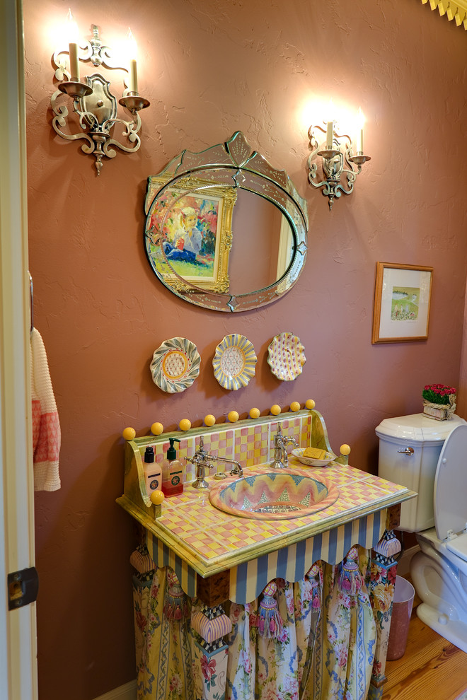 Пример оригинального дизайна: туалет среднего размера в стиле фьюжн с светлым паркетным полом, накладной раковиной, столешницей из плитки, раздельным унитазом, разноцветной плиткой, розовыми стенами и разноцветной столешницей