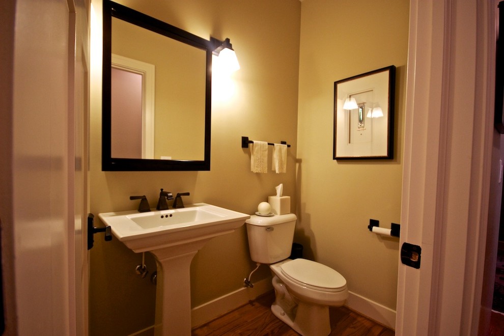 На фото: туалет среднего размера в классическом стиле с раковиной с пьедесталом, раздельным унитазом, бежевыми стенами, темным паркетным полом и коричневым полом с