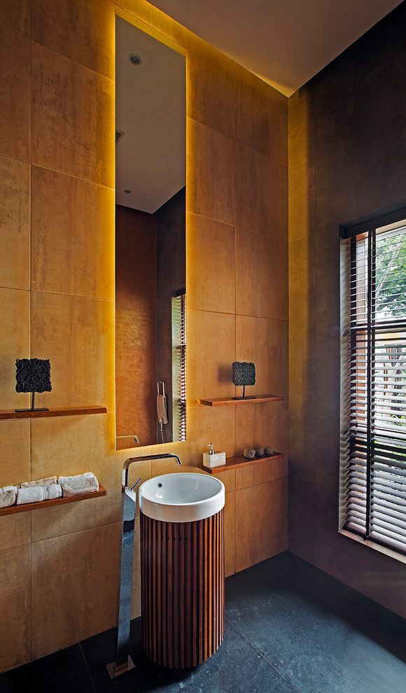 Gästetoilette mit oranger Wandfarbe, Sockelwaschbecken und grauem Boden in Bangalore