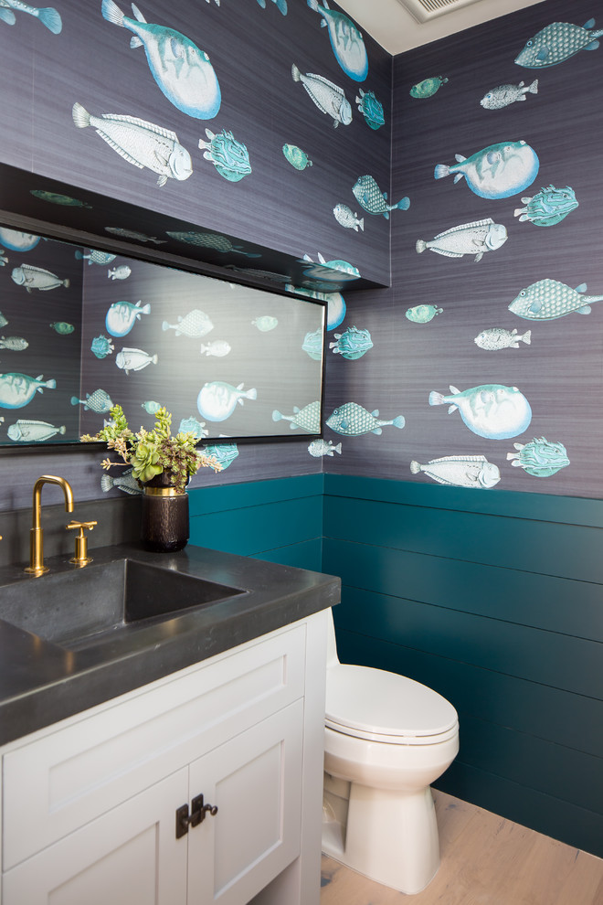 Esempio di un bagno di servizio costiero con ante in stile shaker, ante bianche, WC monopezzo, pareti blu, parquet chiaro, lavabo integrato e top nero