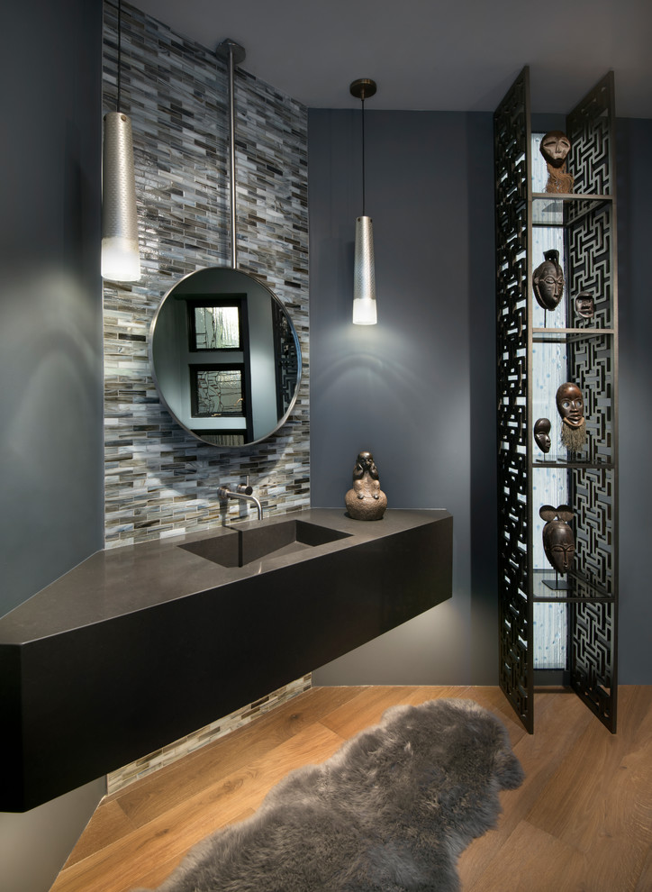 Источник вдохновения для домашнего уюта: туалет в современном стиле с серой плиткой, плиткой мозаикой, серыми стенами, паркетным полом среднего тона, монолитной раковиной, коричневым полом и черной столешницей