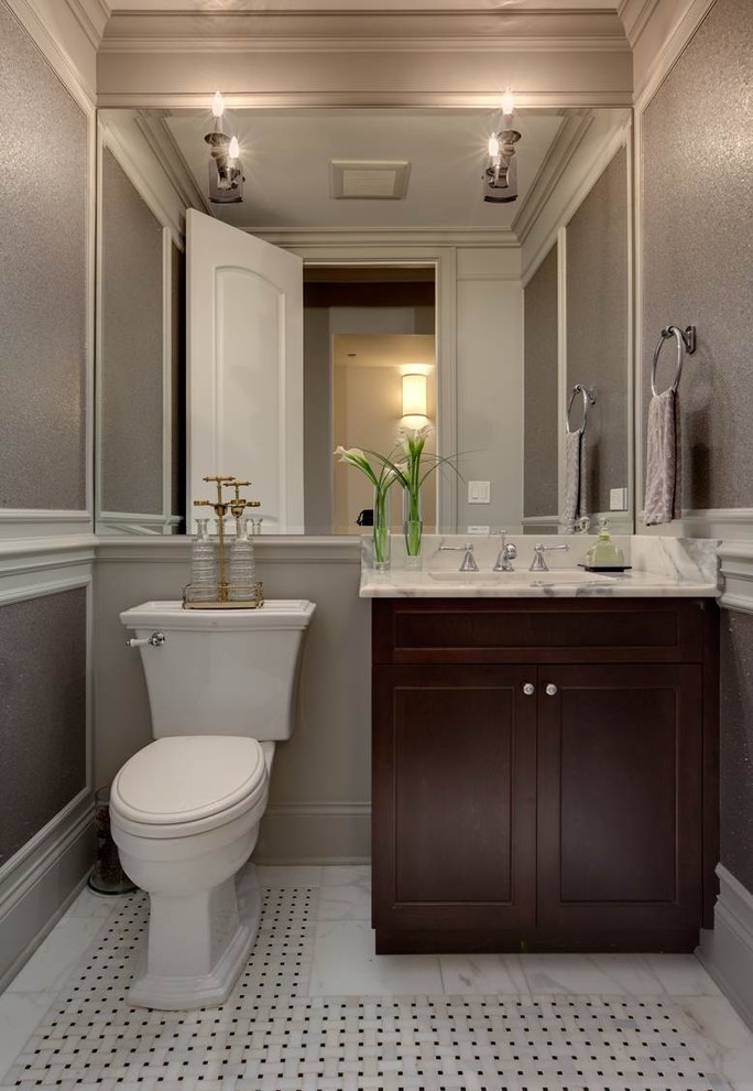 Foto di un bagno di servizio tradizionale di medie dimensioni con ante in stile shaker, ante in legno bruno, WC a due pezzi, pareti grigie, pavimento in marmo, lavabo sottopiano, top in marmo e piastrelle nere