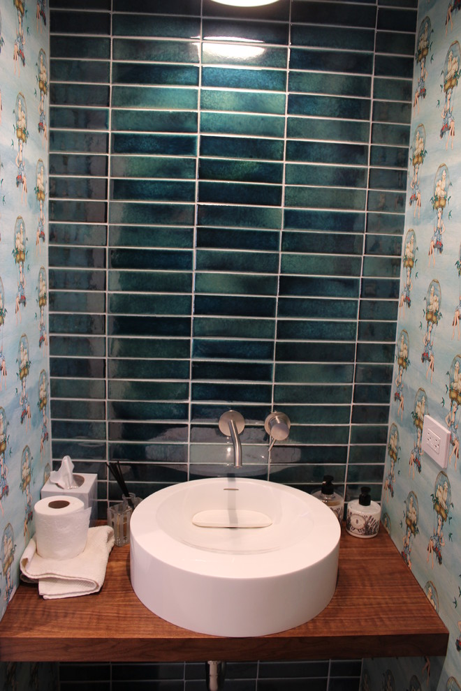 Kleine Moderne Gästetoilette mit dunklen Holzschränken, Wandtoilette, blauen Fliesen, Glasfliesen, bunten Wänden, Betonboden, Aufsatzwaschbecken, Waschtisch aus Holz und grauem Boden in New York