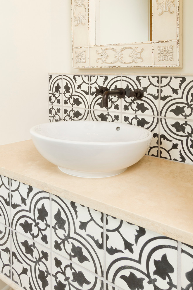 Foto di un piccolo bagno di servizio mediterraneo con lavabo a bacinella, top in pietra calcarea, WC a due pezzi, piastrelle di cemento, pareti bianche e pistrelle in bianco e nero