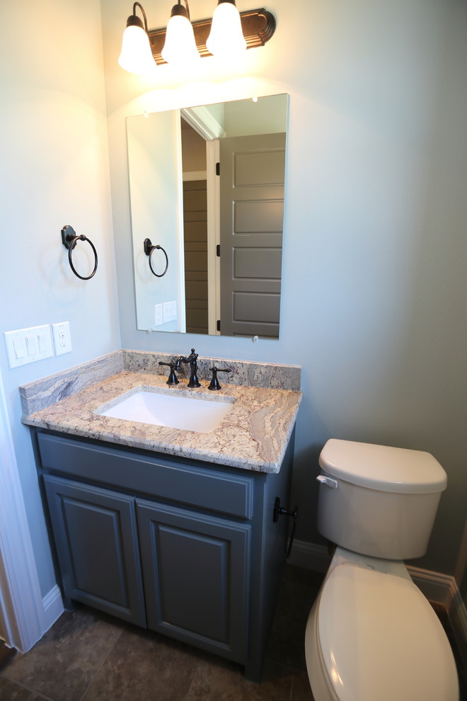 Bild på ett lantligt toalett, med skåp i shakerstil, grå skåp, en toalettstol med hel cisternkåpa, grå väggar, ett nedsänkt handfat och granitbänkskiva