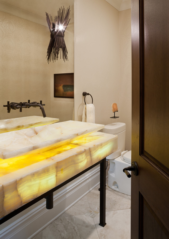 Idéer för mellanstora medelhavsstil gult toaletter, med en toalettstol med separat cisternkåpa, beige väggar, kalkstensgolv, ett fristående handfat, bänkskiva i onyx och beiget golv