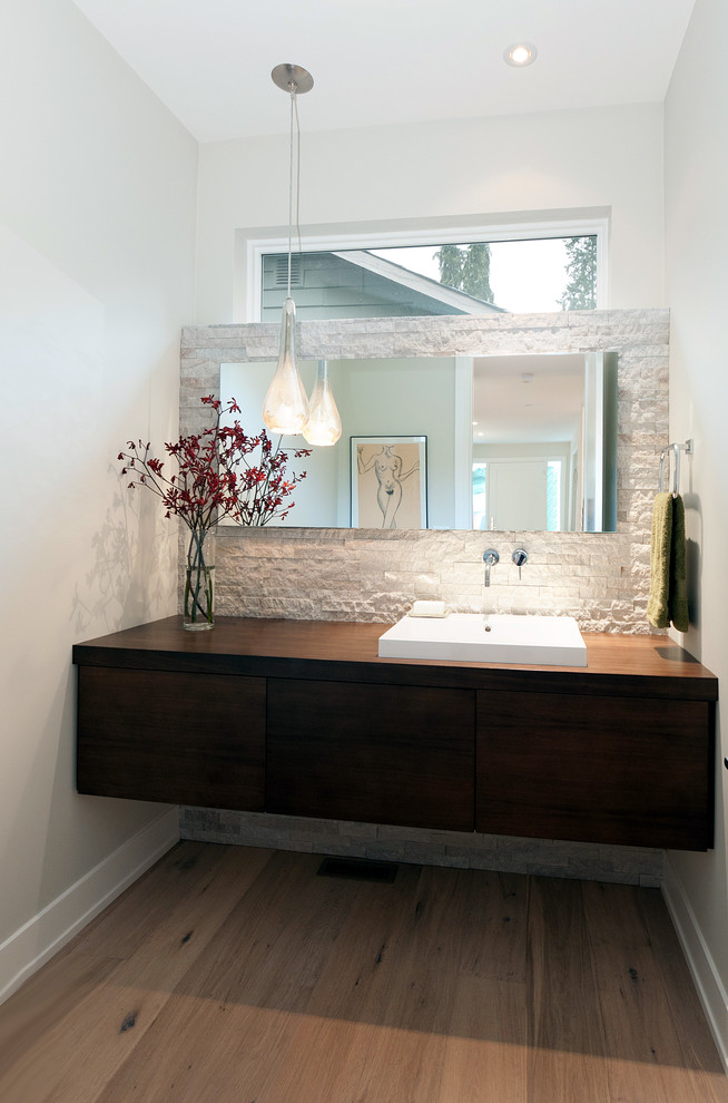 На фото: туалет в современном стиле с накладной раковиной, столешницей из дерева и коричневой столешницей