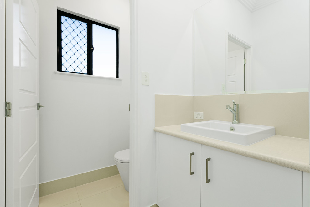 Свежая идея для дизайна: туалет среднего размера с белыми фасадами, керамической плиткой, столешницей из известняка и бежевой плиткой - отличное фото интерьера