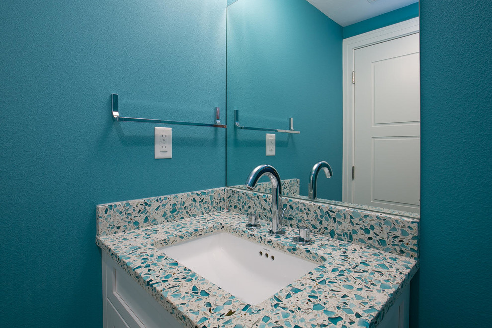 Cette image montre un petit WC et toilettes design avec un placard à porte shaker, un plan de toilette en surface solide, des portes de placard blanches et un plan de toilette turquoise.