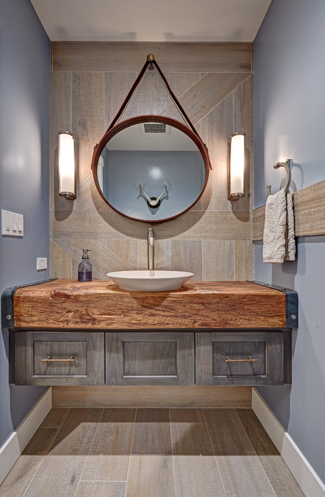 Inspiration for a small cottage gray tile and porcelain tile porcelain tile powder room remodel in Sacramento with a vessel sink, recessed-panel cabinets, gray cabinets, wood countertops, blue walls and brown countertops