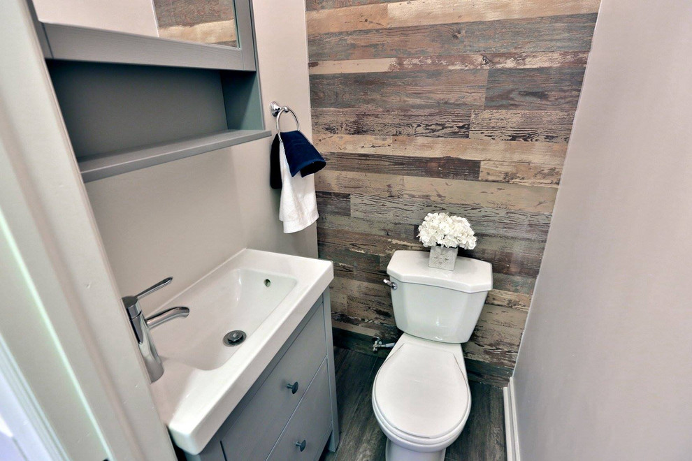 Inspiration for a small transitional ceramic tile and brown floor powder room remodel in Toronto with flat-panel cabinets, gray cabinets, a two-piece toilet, gray walls, an integrated sink and solid surface countertops