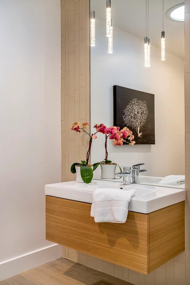 На фото: туалет в стиле модернизм с плоскими фасадами, коричневой плиткой, плиткой кабанчик, белыми стенами, светлым паркетным полом, монолитной раковиной, бежевым полом и белой столешницей