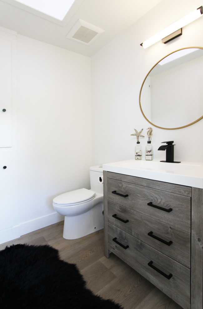 Cette photo montre un petit WC et toilettes chic en bois brun avec un placard à porte plane, WC à poser, un mur blanc, un sol en vinyl, un lavabo intégré, un sol marron, un plan de toilette blanc et meuble-lavabo sur pied.
