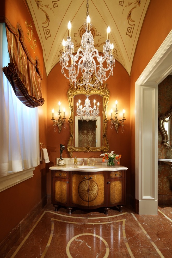 Esempio di un bagno di servizio chic con lavabo sottopiano, consolle stile comò, ante in legno scuro e pareti arancioni