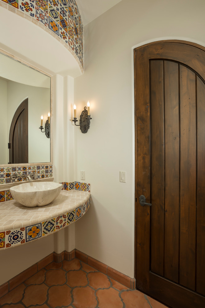 Пример оригинального дизайна: туалет среднего размера в средиземноморском стиле с настольной раковиной, разноцветной плиткой, белыми стенами, полом из терракотовой плитки, столешницей из плитки и цементной плиткой