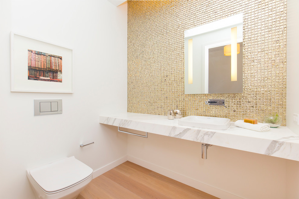 Medium sized contemporary cloakroom in San Francisco with a wall mounted toilet, white walls, light hardwood flooring, a built-in sink, marble worktops, metal tiles and beige floors.