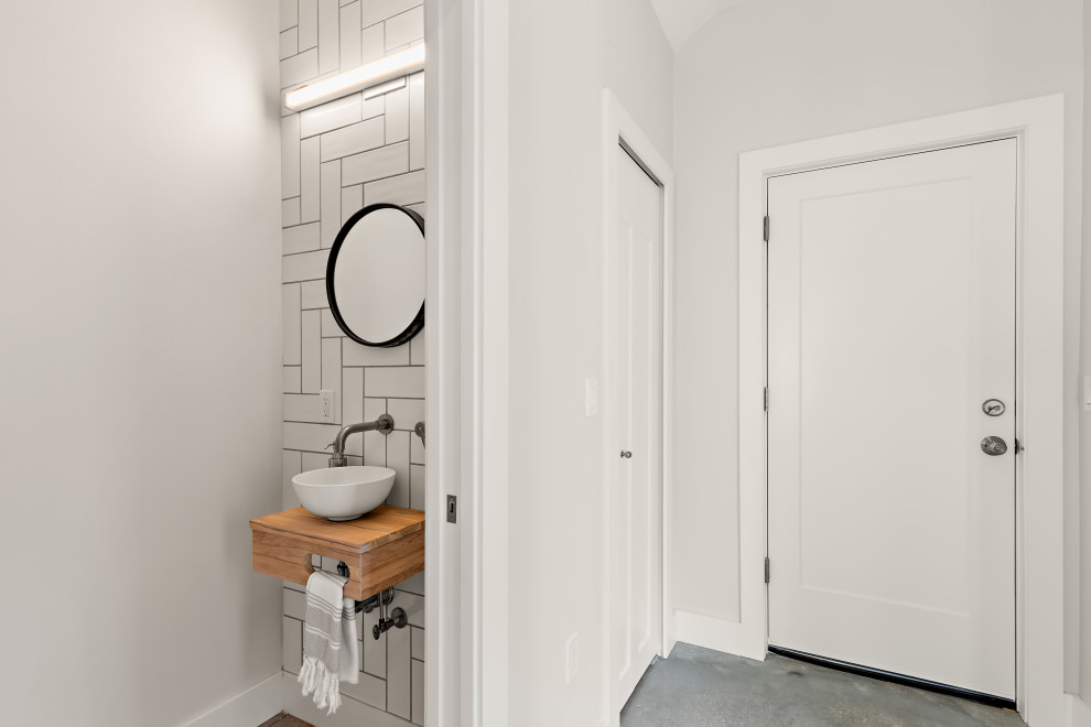 На фото: маленький туалет в стиле кантри с белой плиткой, керамической плиткой, бетонным полом, настольной раковиной, столешницей из дерева, серым полом и подвесной тумбой для на участке и в саду с