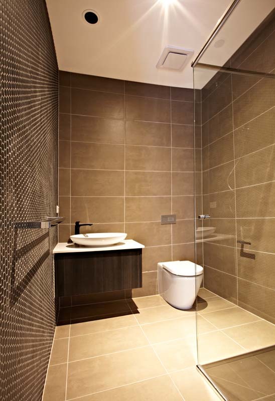 Mittelgroße Moderne Gästetoilette mit flächenbündigen Schrankfronten, braunen Schränken, Wandtoilette, braunen Fliesen, brauner Wandfarbe, Aufsatzwaschbecken und beigem Boden in Melbourne