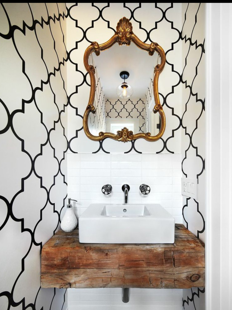 Пример оригинального дизайна: туалет в современном стиле с настольной раковиной, столешницей из дерева, белой плиткой, разноцветными стенами и коричневой столешницей