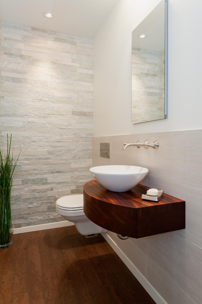 Powder room - modern gray tile and stone tile brown floor powder room idea in Seattle with white walls, a vessel sink and wood countertops