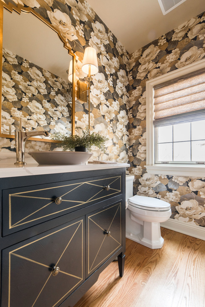Cette image montre un WC et toilettes traditionnel de taille moyenne avec un placard en trompe-l'oeil, des portes de placard noires, WC séparés, un sol en bois brun, une vasque, un plan de toilette en quartz modifié, un sol marron et un plan de toilette blanc.