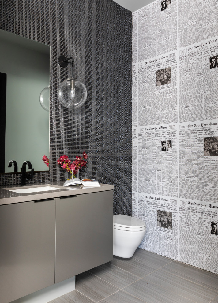 Cette image montre un WC suspendu design avec un placard à porte plane, des portes de placard grises, un mur multicolore, un lavabo encastré, un sol gris et un plan de toilette beige.
