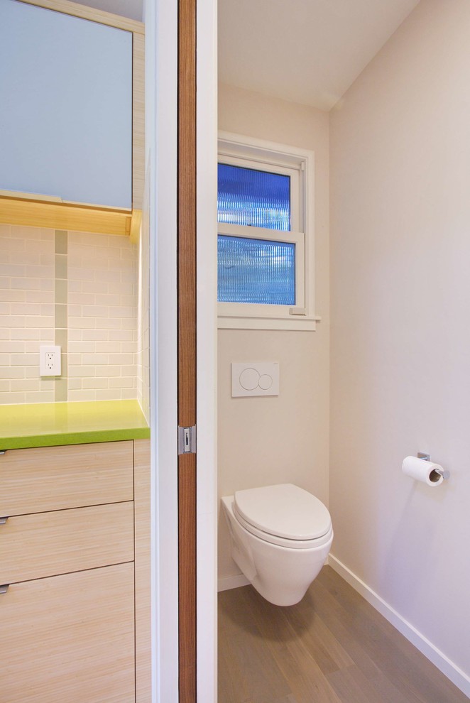 Réalisation d'un petit WC suspendu design avec un mur beige, un sol en bois brun et un sol marron.