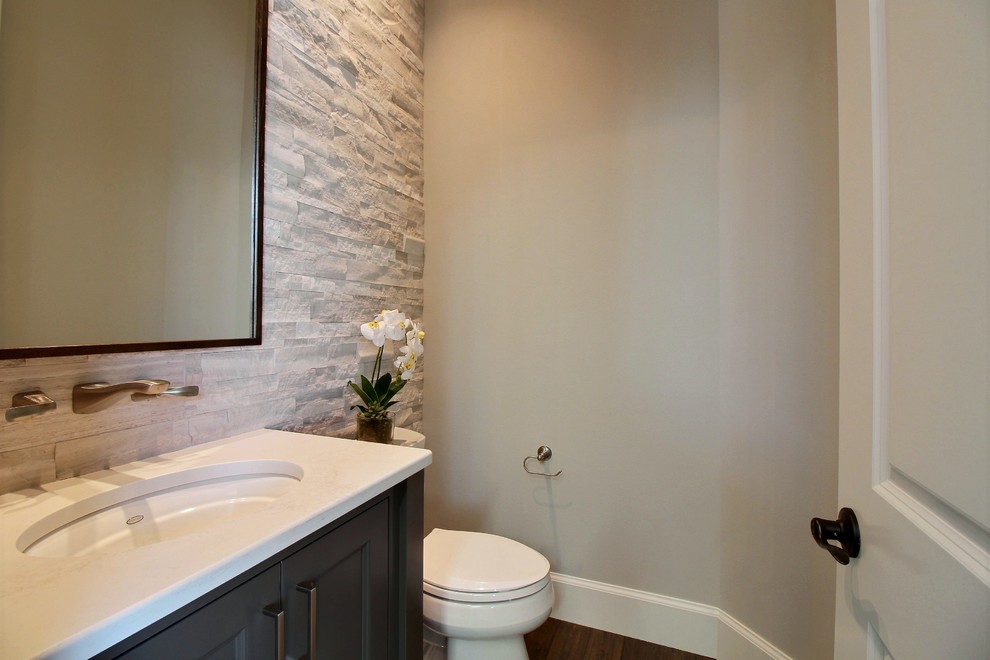 Powder room - mid-sized craftsman multicolored tile and ceramic tile ceramic tile and gray floor powder room idea in Portland with recessed-panel cabinets, dark wood cabinets, a two-piece toilet, gray walls, an undermount sink, quartz countertops and white countertops