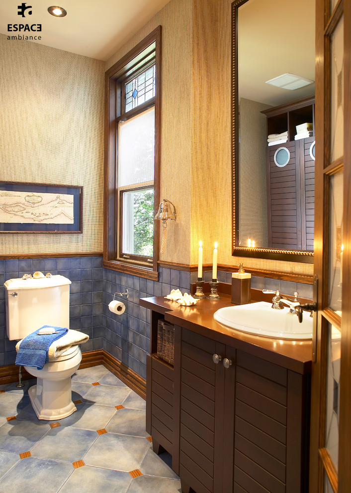Cette photo montre un petit WC et toilettes chic avec des portes de placard marrons, des carreaux de céramique, un mur gris, un lavabo posé, un plan de toilette en bois, un placard à porte shaker, WC à poser, un carrelage bleu et un sol en carrelage de porcelaine.