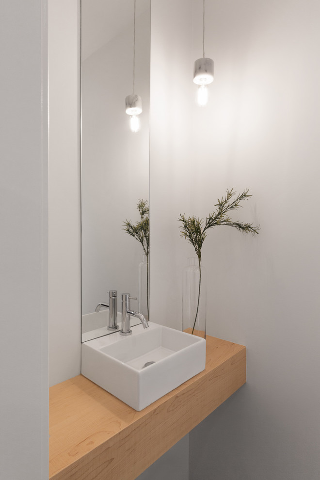 Идея дизайна: маленький туалет в современном стиле с открытыми фасадами, инсталляцией, белой плиткой, керамической плиткой, белыми стенами, полом из керамической плитки, настольной раковиной, столешницей из дерева и серым полом для на участке и в саду