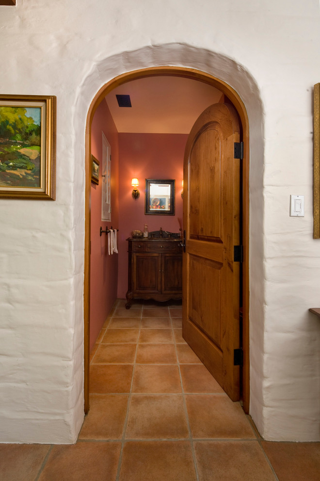 Mittelgroße Mediterrane Gästetoilette mit verzierten Schränken, dunklen Holzschränken, Terrakottaboden und Waschtisch aus Holz in Santa Barbara