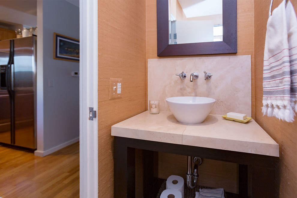 Cette photo montre un petit WC et toilettes bord de mer en bois foncé avec un placard sans porte, WC séparés, un mur beige, une vasque et un plan de toilette en travertin.