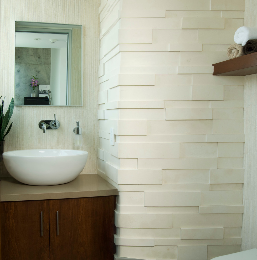 Idée de décoration pour un WC et toilettes minimaliste en bois foncé de taille moyenne avec un placard avec porte à panneau encastré, un carrelage beige, du carrelage en travertin, un mur beige, une vasque et un plan de toilette en quartz modifié.