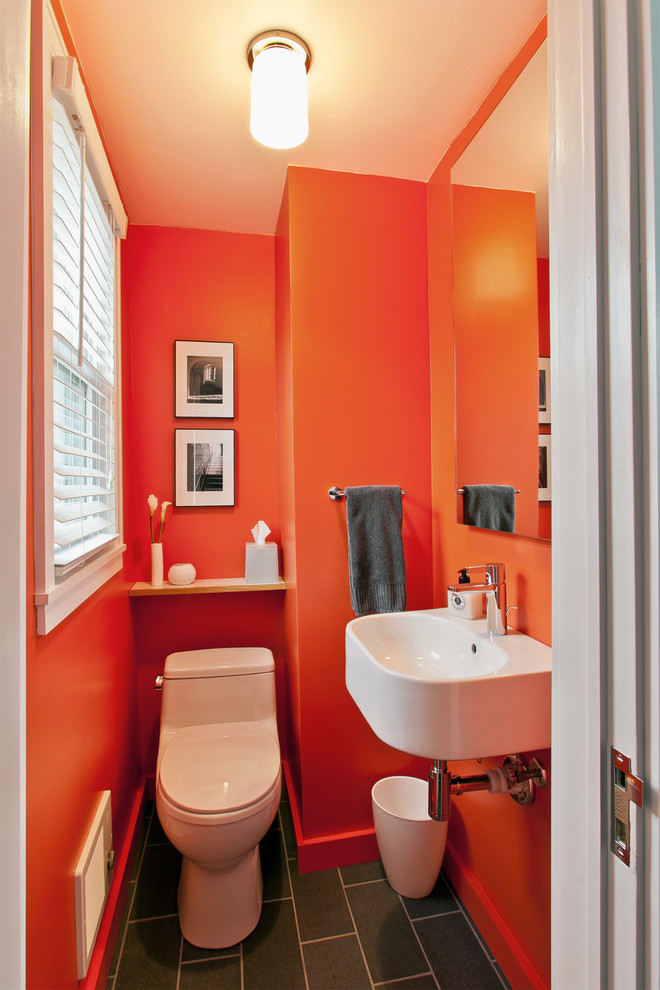 ニューヨークにある小さなモダンスタイルのおしゃれなトイレ・洗面所 (壁付け型シンク、一体型トイレ	、黒いタイル、オレンジの壁、セラミックタイルの床) の写真