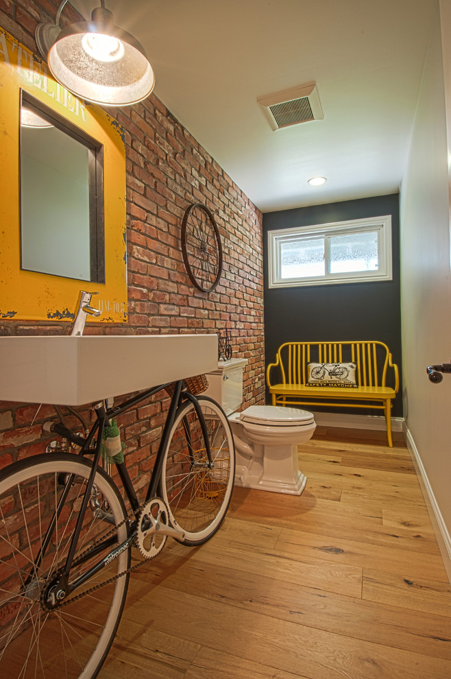 Foto di un bagno di servizio industriale con lavabo sospeso, WC a due pezzi e pavimento in legno massello medio
