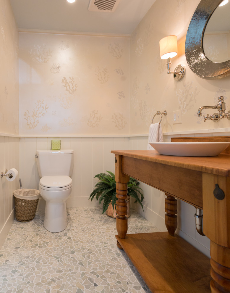 Foto på ett mellanstort maritimt toalett, med möbel-liknande, skåp i mellenmörkt trä, en toalettstol med separat cisternkåpa, flerfärgad kakel, stenkakel, flerfärgade väggar, mosaikgolv, ett fristående handfat och träbänkskiva
