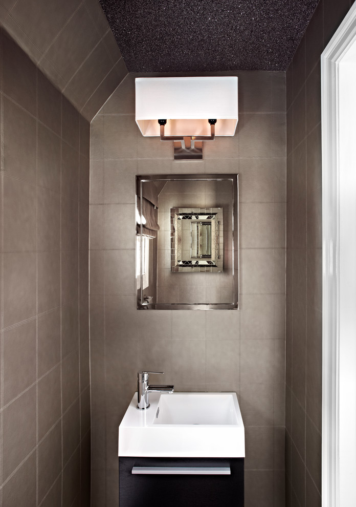 Cette photo montre un petit WC et toilettes tendance en bois foncé avec un lavabo intégré, un placard à porte plane, WC à poser, parquet foncé et un mur gris.