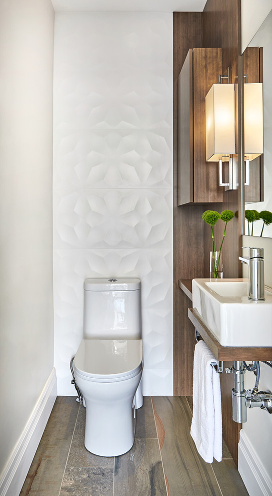 Small contemporary cloakroom in Raleigh with flat-panel cabinets, medium wood cabinets, a two-piece toilet, white tiles, porcelain tiles, porcelain flooring, wooden worktops, brown worktops, a wall-mounted sink, brown floors and beige walls.