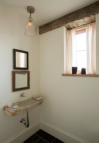 Imagen de aseo de estilo de casa de campo de tamaño medio con paredes blancas, suelo de pizarra, lavabo suspendido, sanitario de pared, encimera de mármol y suelo negro