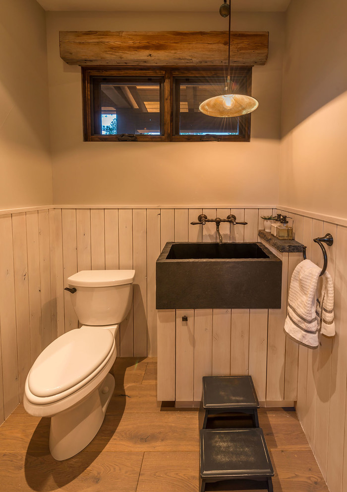 Foto di un bagno di servizio stile rurale con WC a due pezzi, pareti beige, pavimento in legno massello medio, consolle stile comò e ante con finitura invecchiata