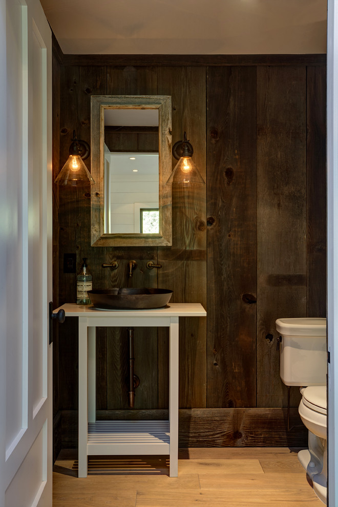 Foto de aseo de estilo de casa de campo de tamaño medio con sanitario de una pieza, paredes marrones, suelo de madera clara y lavabo sobreencimera