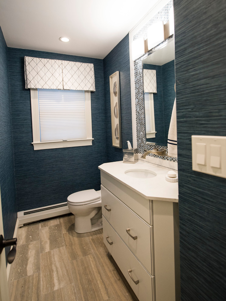 Small traditional cloakroom in Boston with flat-panel cabinets, white cabinets, a one-piece toilet, blue tiles, glass sheet walls, blue walls, ceramic flooring, a submerged sink and beige floors.