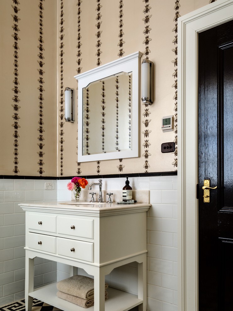 Inredning av ett lantligt stort toalett, med vita skåp, vit kakel, keramikplattor, ett undermonterad handfat, marmorbänkskiva, beige väggar och öppna hyllor