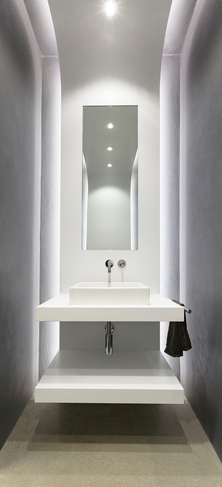 Idées déco pour un WC et toilettes industriel avec un mur gris, sol en béton ciré, une vasque, un plan de toilette en quartz modifié, un sol gris et un placard sans porte.