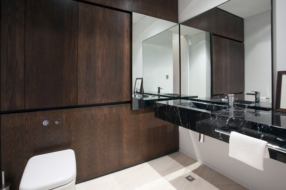 Immagine di un bagno di servizio minimal con lavabo integrato, ante lisce, ante in legno bruno, top in marmo e pavimento in travertino