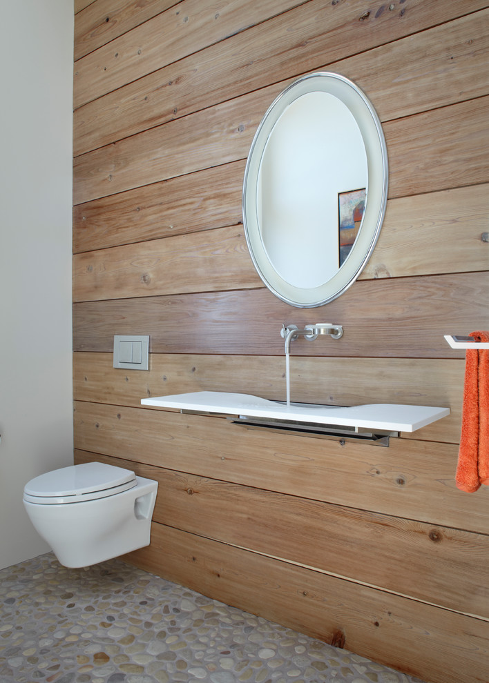 Moderne Gästetoilette mit Wandwaschbecken, Wandtoilette und Kiesel-Bodenfliesen in Sonstige