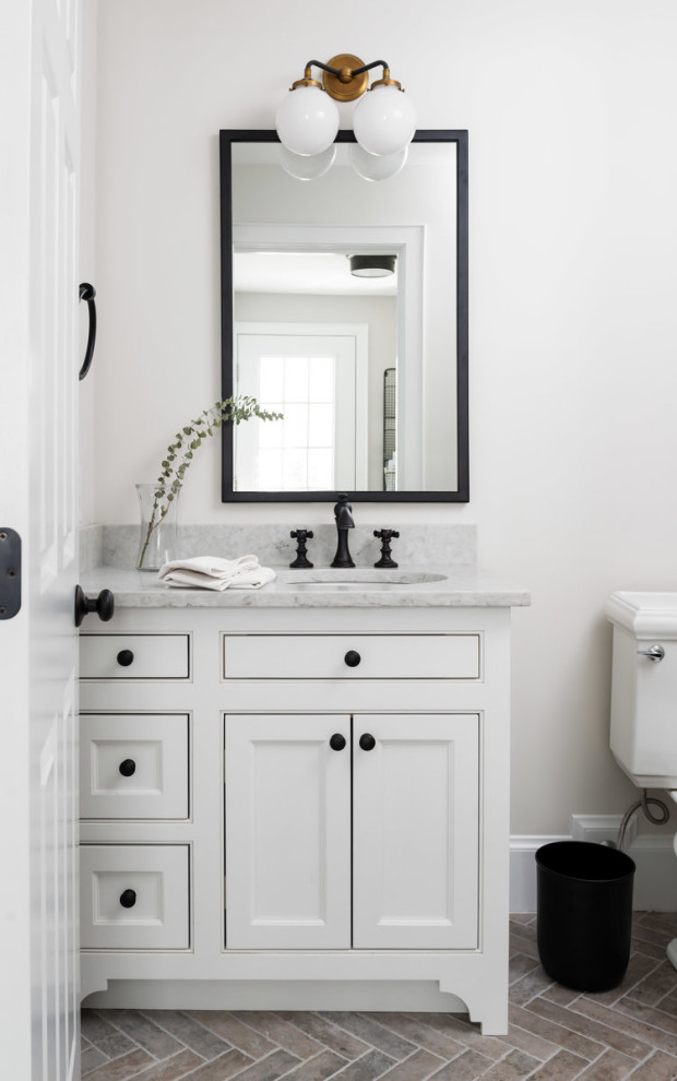Exemple d'un WC et toilettes tendance de taille moyenne avec un placard en trompe-l'oeil, des portes de placard blanches, WC séparés, un mur gris, un sol en carrelage de porcelaine, un lavabo encastré, un plan de toilette en marbre, un sol marron et un plan de toilette gris.